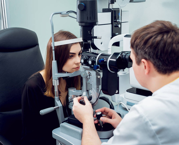 Young woman checking her vision with ophthalmologist. Medical equipment. - 写真・画像