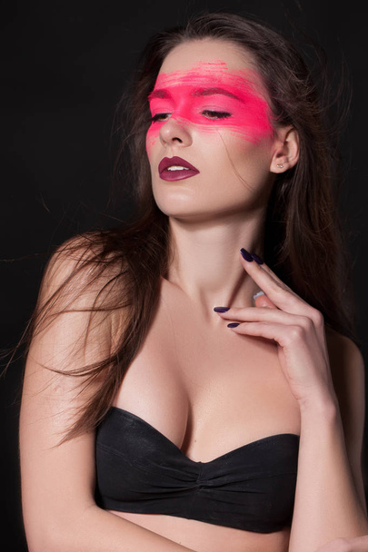 Stylish woman with bright makeup on her Face, Pink Face, shadows. Extreme Makeup Cosmetic Creation Using Color. elegant young woman with gorgeous hair and makeup on black studio background - 写真・画像
