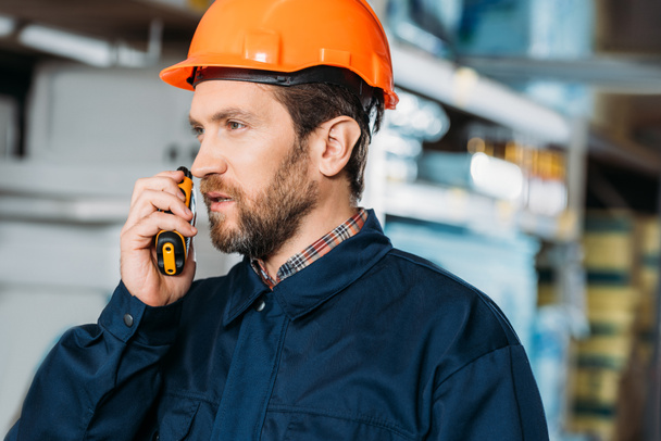 mannelijke werknemer in helm met walkie talkie in de scheepvaart voorraad - Foto, afbeelding