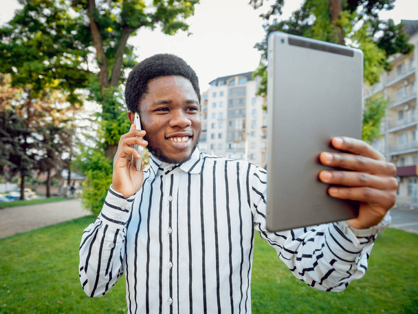 Young african man using tablet in green city park - Foto, immagini