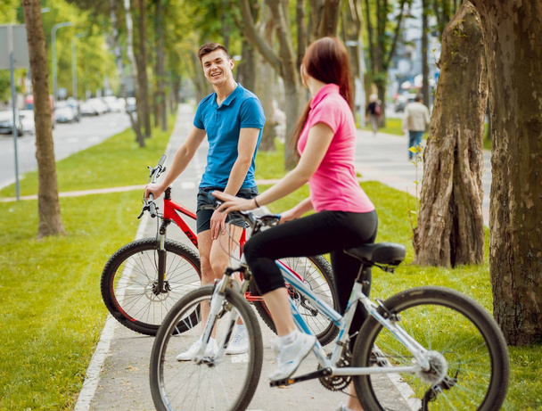 Young caucasian couple cycling on green bicycle lane in sunny day - Foto, Bild