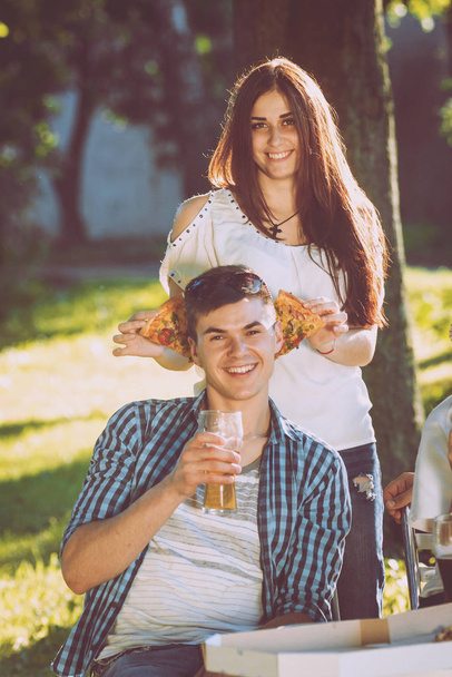 Cheerful caucasian friends on picnic in the park. Smiling and talking. - Foto, imagen