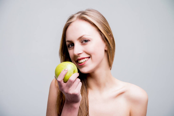 Studio portrait of beautiful naked caucasian woman with apple. - Zdjęcie, obraz