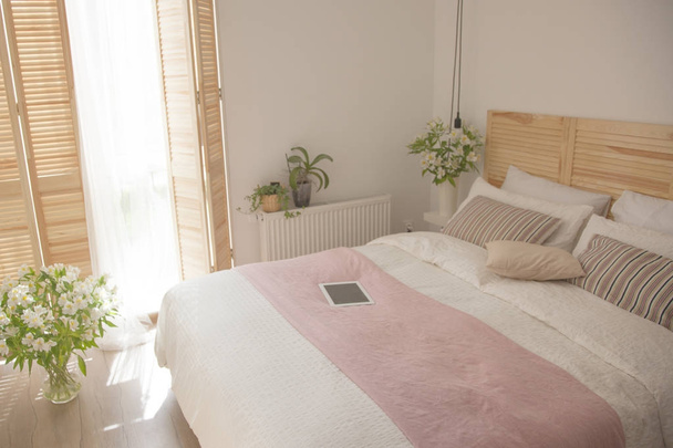 Moderno interno camera da letto con fiori in vasi e laptop sul letto
 - Foto, immagini