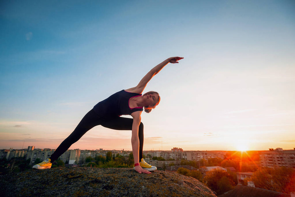 Young girl practicing yoga on the roof at sunset. - Foto, Imagem