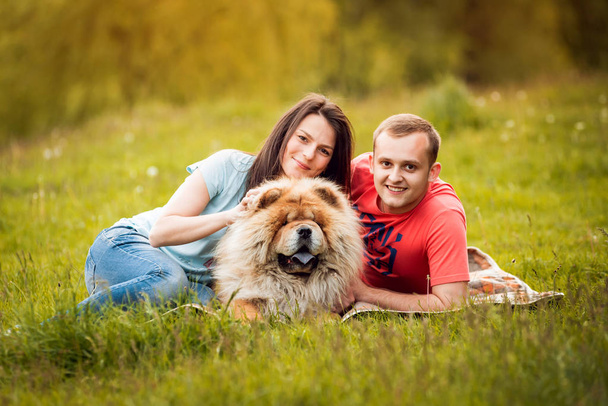 Young couple with their dog chow-chow walking in the park and having good time - Zdjęcie, obraz