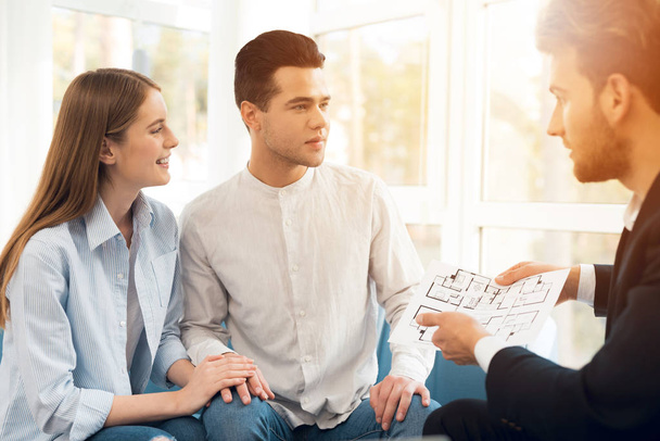 Young couple in a meeting with a realtor. Guy and girl make a contract with realtor buying property. - Fotoğraf, Görsel