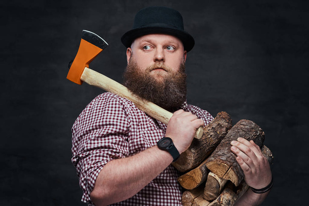 Retrato de um homem gordo hipster detém lenha e um machado sobre fundo cinza
. - Foto, Imagem