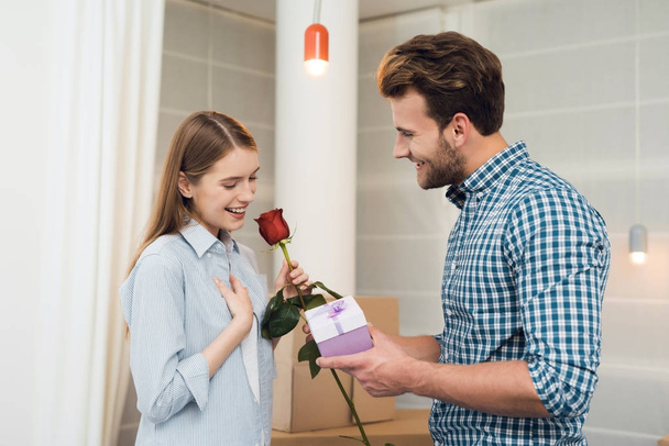 Guy gives his girlfriend a rose and gift. Girl is very happy with the gifts from the guy. - Fotó, kép