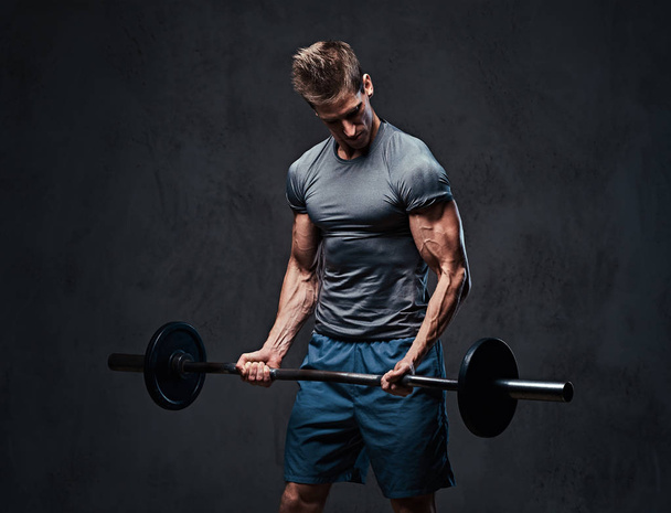 Athletic male biceps barbell workout. Studio portrait over grey background. - Photo, Image