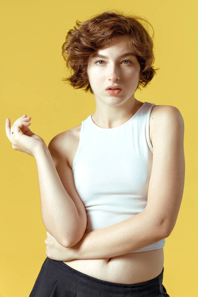 Hermosa y emotiva chica sobre un fondo amarillo sin maquillaje y con piel natural
 - Foto, Imagen