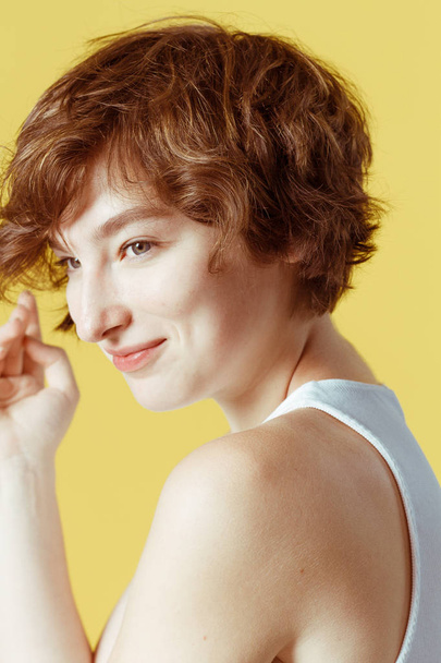 Beautiful and emotional girl on a yellow background without make-up and with natural skin - Foto, Bild