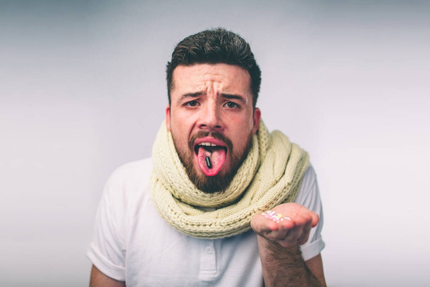 tablet on the tongue of a bearded guy - Φωτογραφία, εικόνα