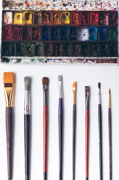 top view of well ordered paintbrushes and watercolour paints at designer workplace   - Foto, immagini