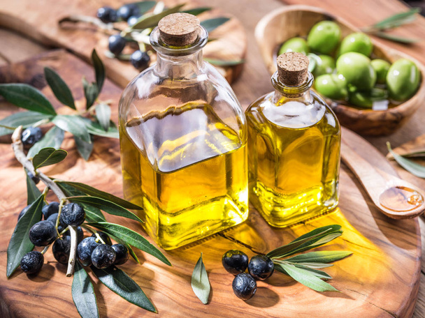 Olive oil and berries are on the olive wooden tray.  - Фото, изображение