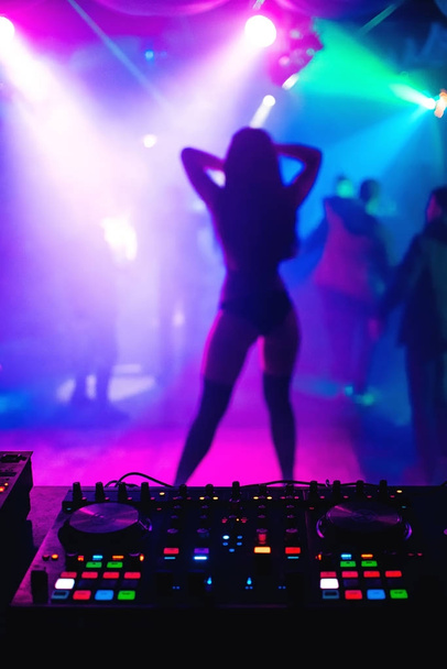 silueta borrosa de bailarina chica delgada en la escena de discoteca en el mezclador de fondo DJ
 - Foto, imagen