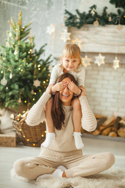 母と幼い娘を楽しんで、クリスマス ツリーや装飾品の背景と対戦. - 写真・画像