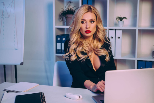mujer seductora que trabaja con el ordenador portátil en la oficina y mirando hacia otro lado
 - Foto, imagen