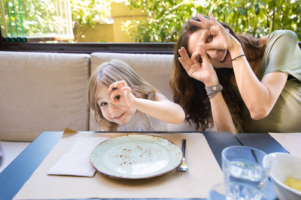 αστείο κορίτσι και μητέρα στο εστιατόριο πειράγματα και βλέπουν - Φωτογραφία, εικόνα