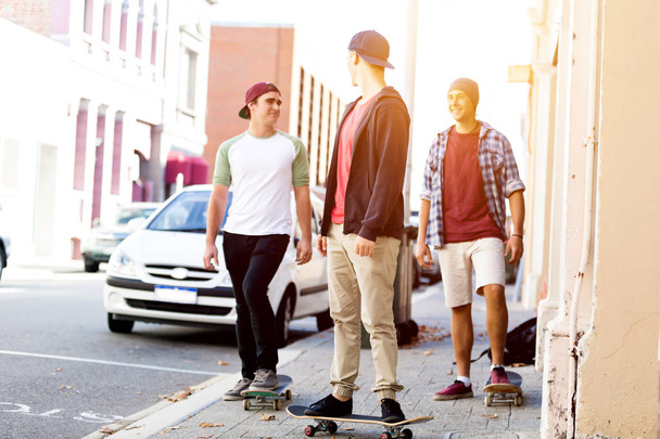 Teenage friends walking at the street with skateboards - Photo, image