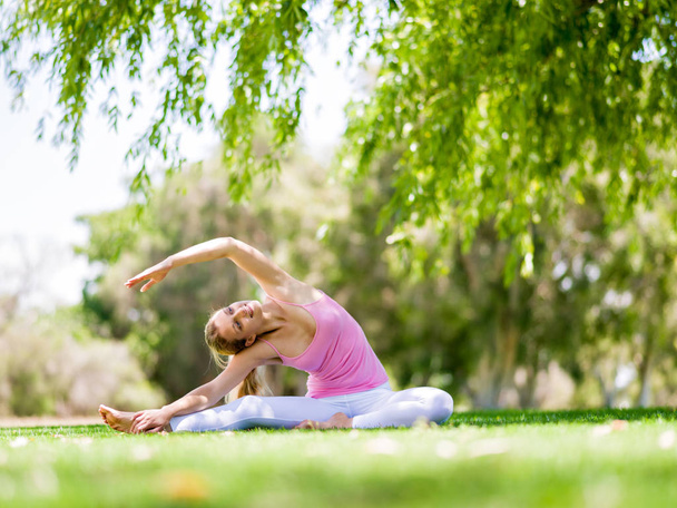 Young woman doing yoga in the park - Fotó, kép