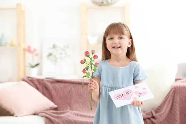 Little girl holding greeting card and flower for Mother's day at home - Foto, immagini
