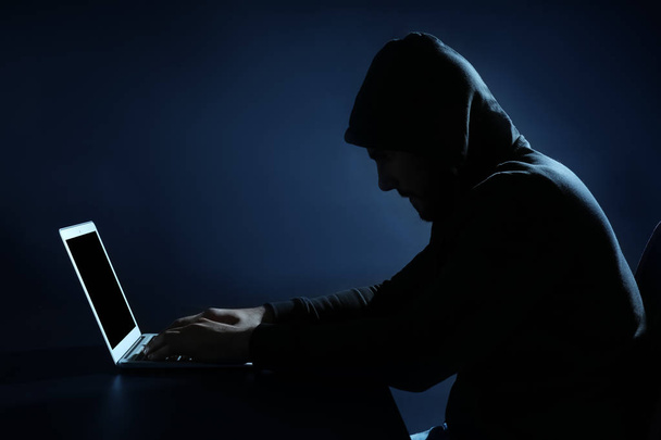 Hacker using laptop on dark background - Fotó, kép