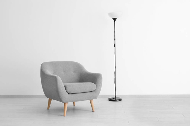 Comfortable armchair and lamp near light wall - Φωτογραφία, εικόνα
