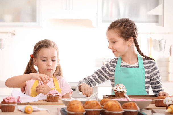 Cute girls decorating cupcakes in kitchen during cooking classes - Фото, зображення