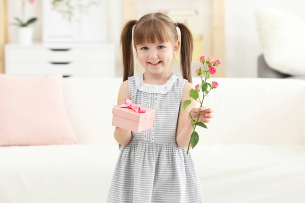 Little girl holding gift box and flower for Mother's day at home - Foto, immagini
