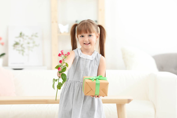 Little girl holding gift box and flower for Mother's day at home - Фото, зображення