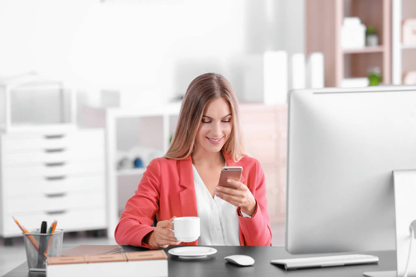 Young woman using smartphone in office - Foto, imagen