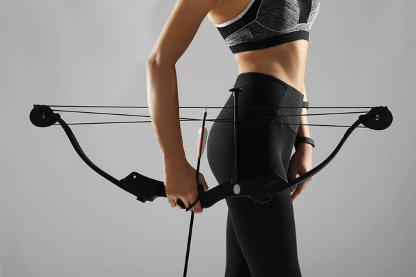 Sporty young woman with bow and arrow for practicing archery on grey background - Φωτογραφία, εικόνα