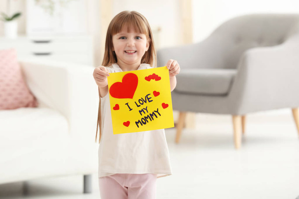 Little girl holding greeting card for Mother's day at home - Foto, Imagen