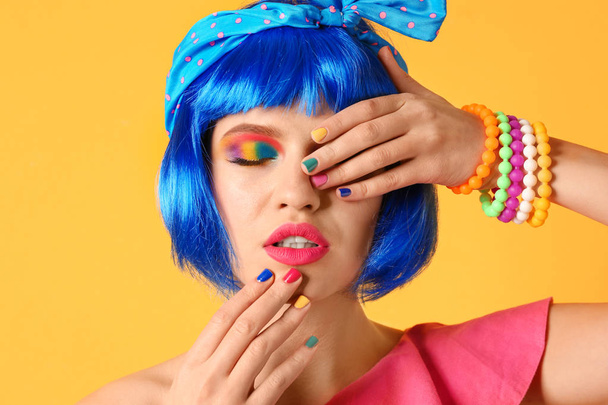 junge Frau mit Regenbogen-Make-up und blauen Haaren auf gelbem Hintergrund - Foto, Bild