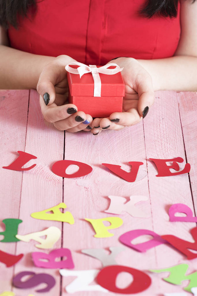 Τη λέξη αγάπη και μια γυναίκα που κρατάει ένα δώρο - Φωτογραφία, εικόνα