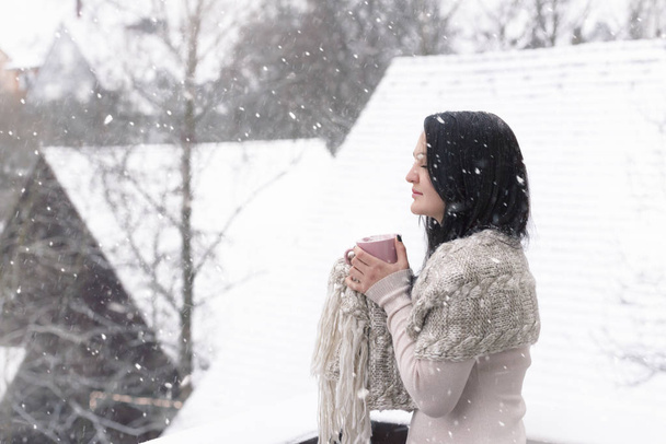 降雪下で温かい飲み物を持つ女性 - 写真・画像