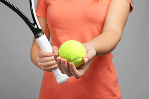 Woman with tennis racket and ball on grey background - Фото, зображення