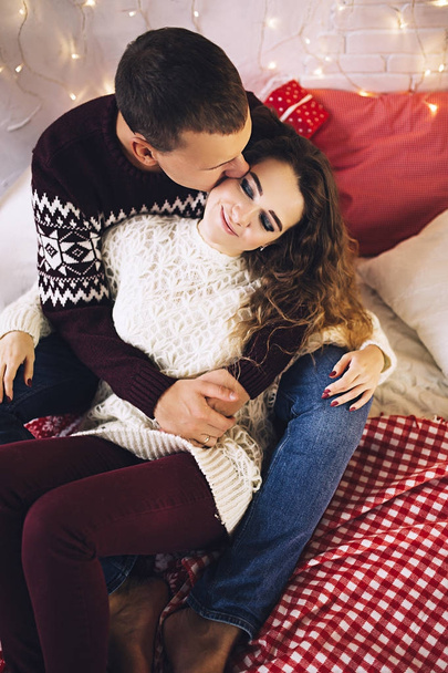 glückliches Paar in den Pullovern küsst und umarmt sich in der Nähe des Weihnachtsbaums, gemütliche Atmosphäre und Liebe, Haus und Familie, weiße kaukasische Paar, verheiratete Menschen - Foto, Bild