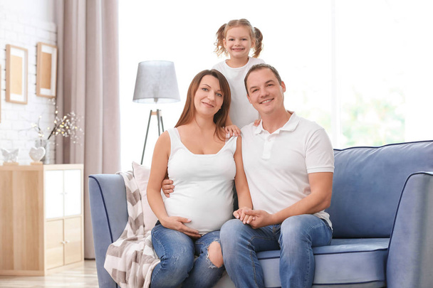 Happy young family on sofa at home - Photo, image