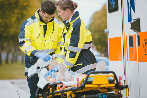 Médicos de emergência que dão oxigénio à vítima
 - Foto, Imagem