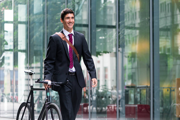 man walking with bicycle near office buildings - Fotoğraf, Görsel