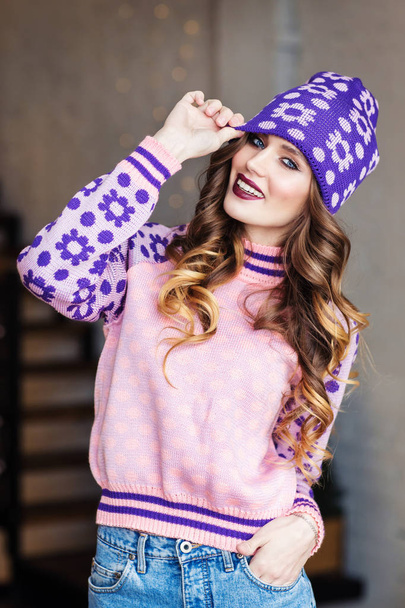 young beautiful girl wearing purple sweater and knitted hat posing indoors - Foto, Imagem