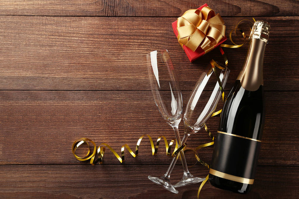 Champagne bottle with glasses and gift box on brown wooden table - Photo, image