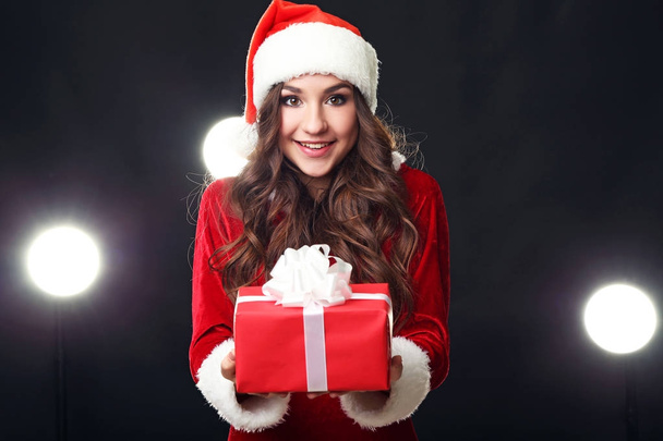 Young woman in red christmas costume holding gift box - Фото, изображение