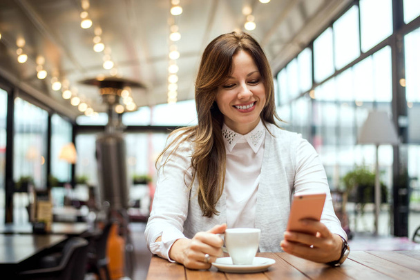 barna nő kávézóban kávét iszik - Fotó, kép
