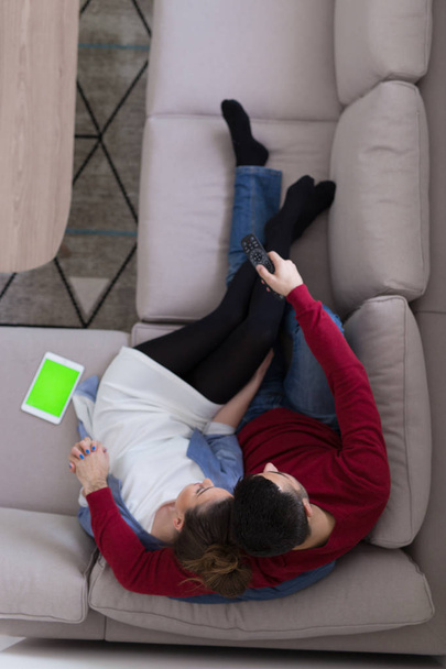 Young couple on the sofa watching television top view - 写真・画像