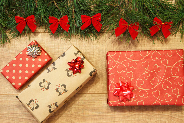 Regali di Capodanno / Natale in pacchetto, albero con fiocchi rossi sul modello di sfondo in legno
 - Foto, immagini