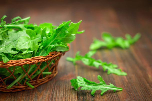 Fresh juicy leaves of arugula on a brown wooden table. - Foto, immagini