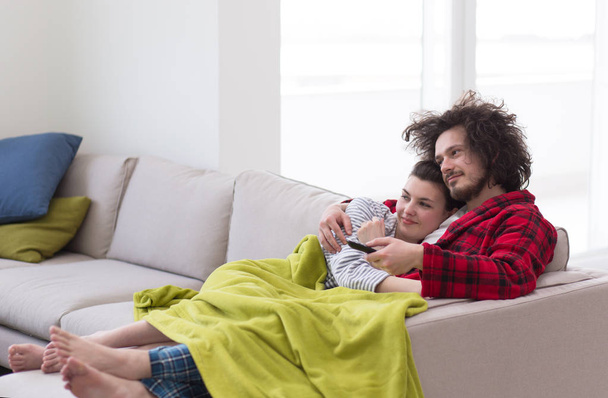Young couple on the sofa watching television - 写真・画像